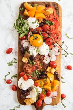 a wooden cutting board topped with lots of different types of vegetables on top of it