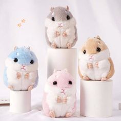 three small stuffed hamsters sitting on top of two toilet paper holders, one in the shape of a hamster