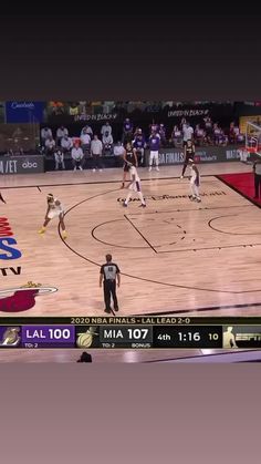 a group of people playing basketball on a court in front of a large screen tv