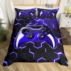 a blue and black bed with two game controllers on the cover, next to a plant