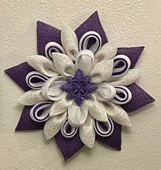 a purple and white flower is hanging on the wall