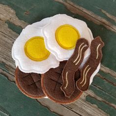 two fried eggs and bacon on top of a wooden table next to a pair of scissors