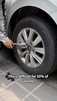 a man is changing the tire on his car with an advertise that reads, this is difficult for 50 % of people