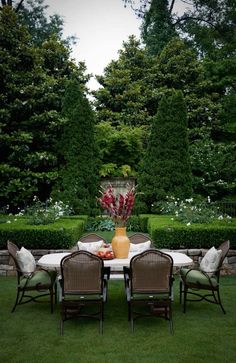 a table with chairs and a vase on it in the middle of a lawn area