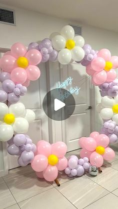 balloons are arranged in the shape of flowers for a birthday party entrance decoration with a video play button