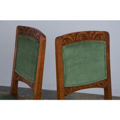 two wooden chairs with green upholstered back and seat cushions, side by side