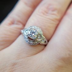 a woman's hand with a diamond ring on top of her finger and an engagement band