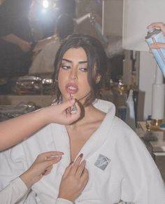 a woman is brushing her teeth while another person holds a hair dryer in front of her