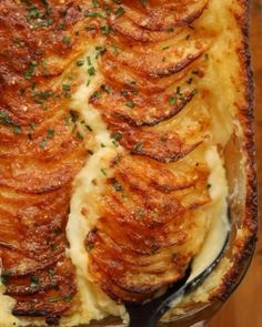 a casserole dish with potatoes and parmesan cheese in it on a wooden table