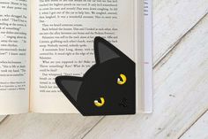 an open book with a black cat's face and yellow eyes on the pages