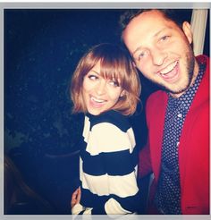 a man standing next to a woman wearing a red jacket and black and white shirt