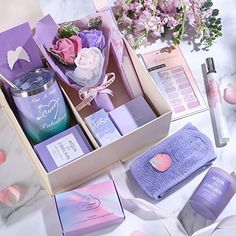 an open box with various items in it on a marble table next to pink flowers