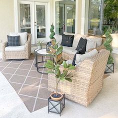 an outdoor living area with wicker furniture and potted plants on the patio floor