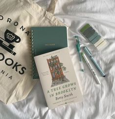 books and pens sitting on top of a bed next to an eco - friendly bag