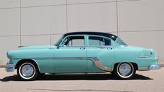 an old blue car parked in front of a building