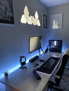 a desk with a monitor, keyboard and headphones sitting on top of it next to a lamp