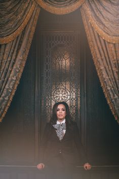 a woman standing in front of a window with curtains