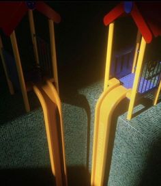 two children's play structures in the dark with blue and yellow seats behind them