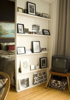 a bedroom with a tv, bookshelf and pictures on the wall