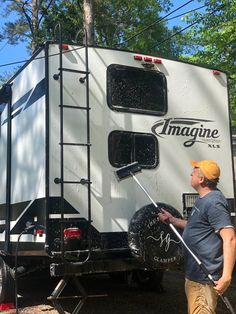 a man is washing his camper on the side of the road in front of some trees