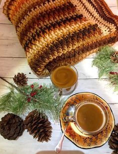 two cups of coffee on a table with pine cones