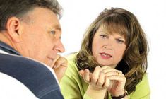 a woman sitting next to a man who is holding his hand on his chin and looking at him