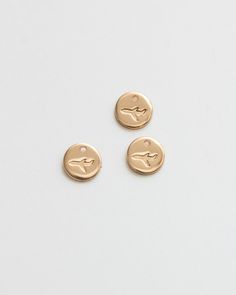 two small gold buttons on a white surface