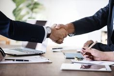 two people shaking hands over a desk with laptops and papers on it, the text reads top 10 ways that a bookkeeper can help your business