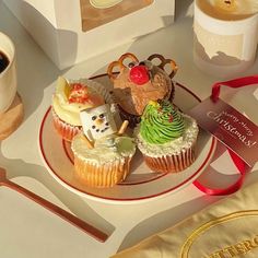 cupcakes with frosting and decorations are on a plate next to two cups of coffee