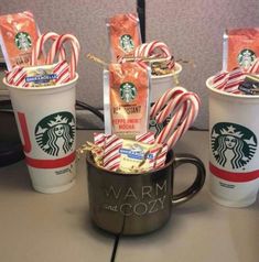 starbucks coffee cups with candy canes in them and wrapped in wrappers on the side