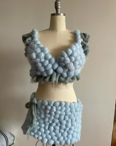 a mannequin wearing a blue and gray crochet skirt with ruffles