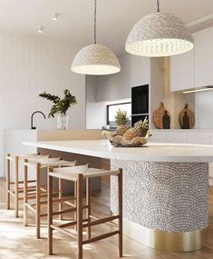 a kitchen with two pendant lights over the island and stools in front of it