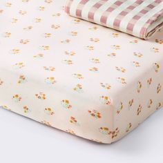 a pink and white checkered bed sheet with flowers on the bottom, along with two matching pillow cases