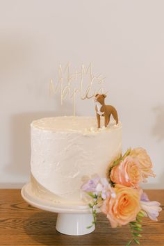 a wedding cake with a deer topper and flowers on the table next to it