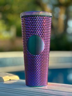 a pink and purple cup sitting on top of a table next to a swimming pool