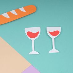 two paper wine glasses next to a carrot on a blue background with other crafting supplies