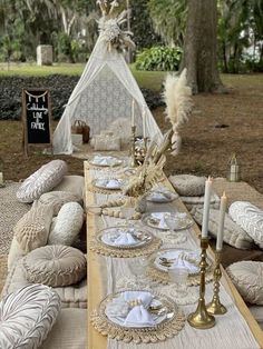 a table set up with plates, candles and napkins for an outdoor dinner party