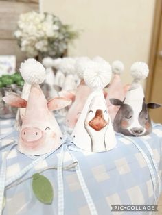 three paper hats with animals on them sitting on a blue and white checkered table cloth