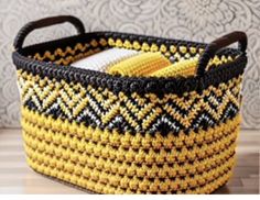 a yellow and black basket sitting on top of a wooden table