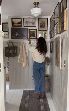 a woman is standing in the hallway with her back to the camera and looking at pictures on the wall