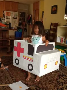 two children playing in a room with cardboard boxes