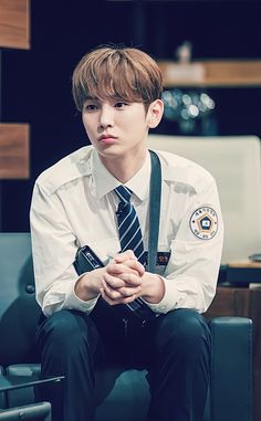 a young man sitting on top of a chair wearing a white shirt and black tie