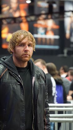 a man standing in front of a crowd wearing a black leather jacket and hoodie