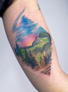 a colorful mountain landscape tattoo on the arm