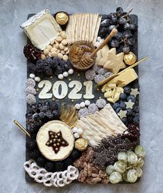 a board with cheese, crackers, grapes, nuts and other items on it