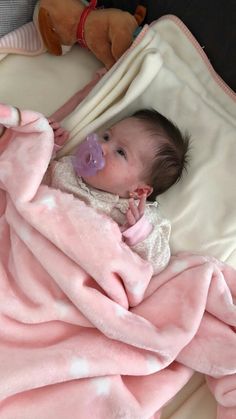 a baby wrapped in a pink blanket with a pacifier