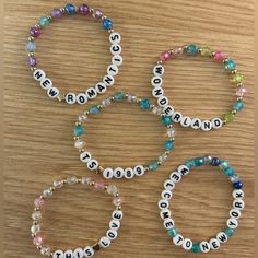 four bracelets with words that spell out the names of people in different colors and sizes