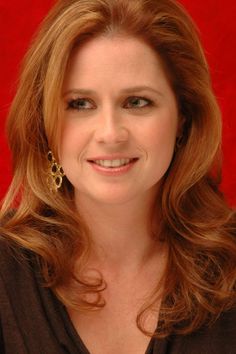 a close up of a person wearing a black shirt and smiling at the camera with a red background