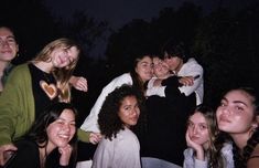 a group of young people posing for a photo at night with their arms around each other