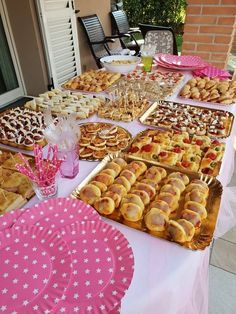 a table topped with lots of pastries on top of a white table covered in pink napkins